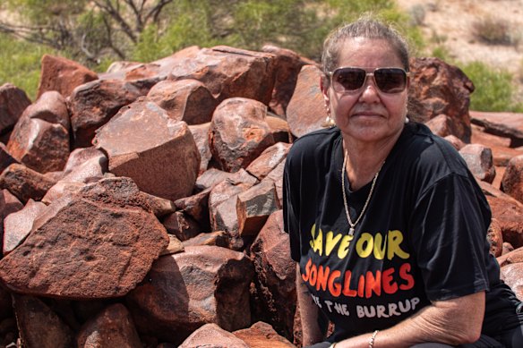 Traditional owner Raelene Cooper with a hand petroglyph on the Burrup Peninsula. The Murujuga cultural landscape contains the first ever artistic depiction of the human face and now-extinct megafauna.