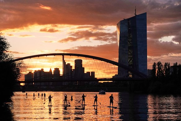 Stand up paddlers navigate the river Main near the European Central Bank, right, in Frankfurt, Germany.