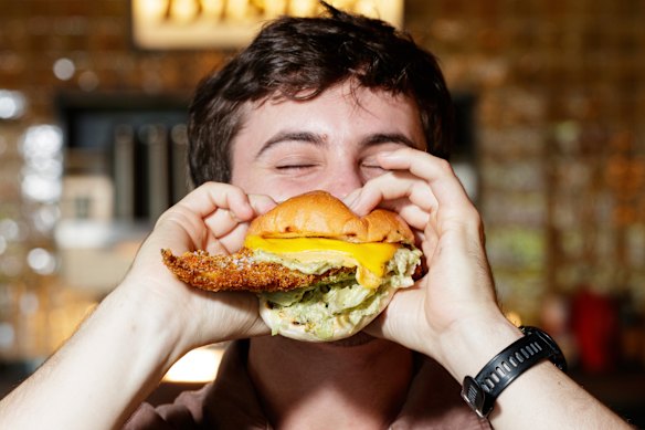 Bartender Hugh MacMaster with the fish burger at The Bat &amp; Ball Hotel in Redfern. 