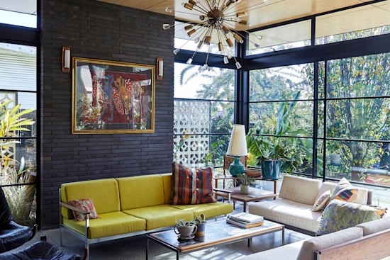 Metal-framed, floor-to-ceiling glass sliding doors and windows are a feature of the home’s brick and steel extension. The painting, titled Frog Spirit Dreaming, is by Alan Dowler Kamara.