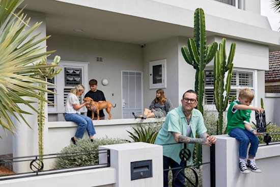 Taking cues from a curved wall in the former red-brick bungalow, the home was given a grand makeover incorporating the sleek P&O style. “It was crucial to add a second storey, as my older kids Frankie (on the porch with Caroline McCredie) and Clementine, need their own space,” says Ben Milgate, at the gate with Mac.