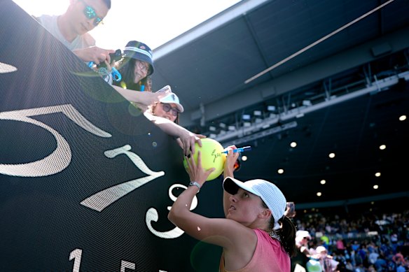Iga Swiatek of Poland signs autographs after winning her quarter-final match.