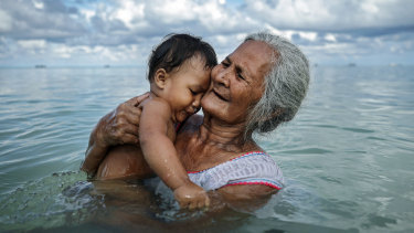 Suega Apelu bathes a child in a lagoon in Tuvalu, one of the Pacific Island nations most threatened by climate change.