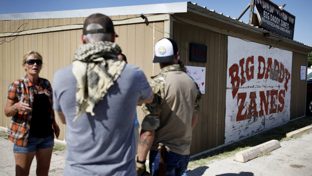 Gabrielle Ellison, left, owner of Big Daddy Zane's bar which has been re-opened, speaks with a group of protesters outside of her bar in Odessa, Texas. 