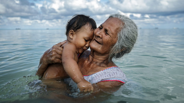 Suega Apelu bathes a child in a lagoon in Tuvalu, one of the Pacific Island nations most threatened by climate change.