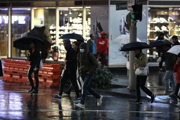 Pedestrians brave the rain in Sydney's CBD on Friday night.