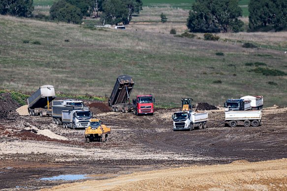 Heavy vechicles unload cleanfill onto the dam site.