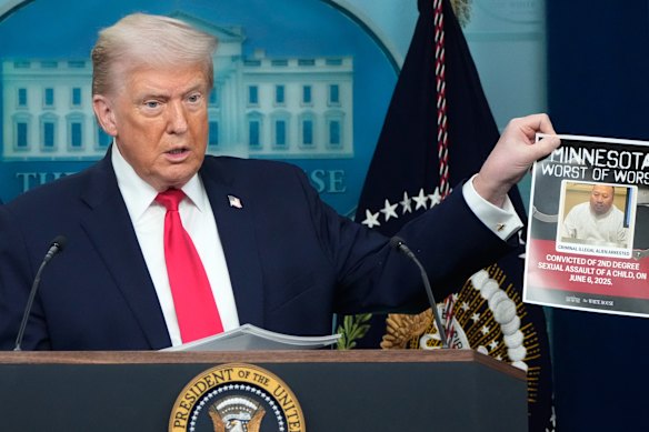 Trump mengangkat poster tersangka penjahat migran yang ditangkap oleh ICE.