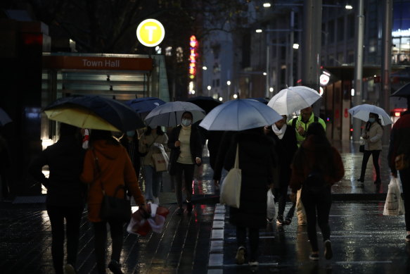 Pedestrians endure a wet and gloomy walk through the Sydney CBD on Friday.