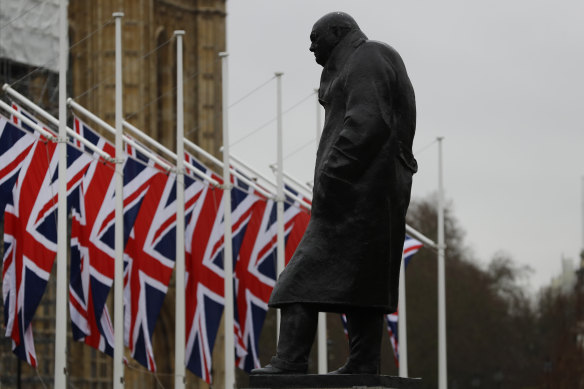 Union Jack flags hang outside Parliament near a statue of former prime minister Winston Churchill. 