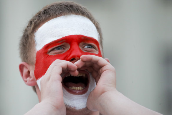 A man with a face painted with the old Belarusian national flag, shouts during opposition rally in front of the government building of Minsk.