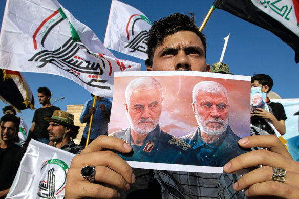 A supporter of an Iran-backed militia holds a poster of slain Iranian General Qassem Soleimani, left, and deputy commander Abu Mahdi al-Muhandis during a protest by pro-Iranian militiamen in Iraq last year.