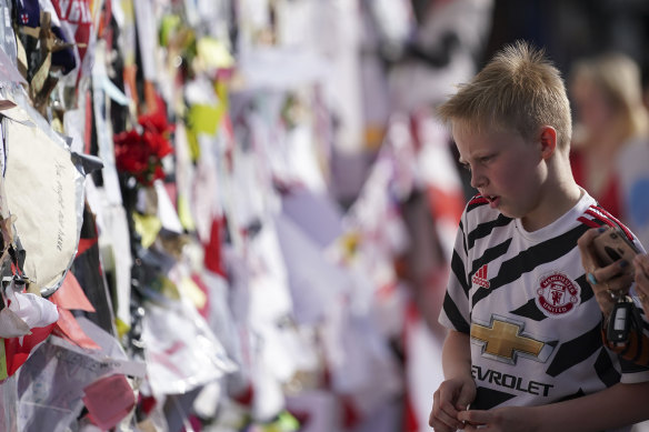 A boy looks at the messages left on the wall in Manchester.
