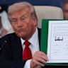 Donald Trump holds a signed document during a summit to support ending the war in Gaza. 