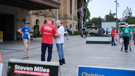 Party volunteers speak to voters at Brisbane City Hall on the first day of early voting in the 2024 state election.