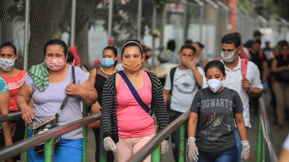 Workers wear masks as a protection against the spread of the new coronavirus as they leave from a day's work in Managua.