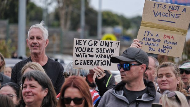 A protester at Health Minister Greg Hunt’s Mornington Peninsula electorate office holds a sign claiming the COVID vaccine is a poison that will alter people’s DNA. 