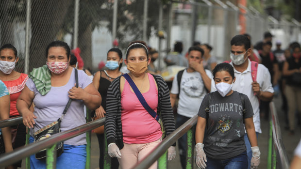 Workers wear masks as a protection against the spread of the new coronavirus as they leave from a day's work in Managua.