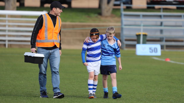'In a world full of Covid – be kind': Brody Grainger, 9, a player for St Edmund's College being comforted by Marist opponent Theo Campton, 10, at a weekend junior rugby game last weekend in Canberra, with Dr Michael Koppman also helping out.