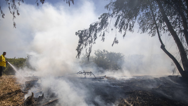 A firefighter on the Israeli side of the border extinguishes a fire that Israel says was started by an incendiary device launched from the Gaza Strip