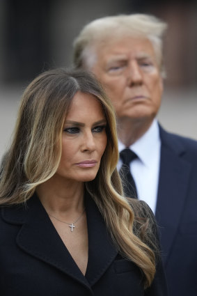 Former president Donald Trump stands behind his wife Melania as she watches pallbearers carry the coffin of her mother, Amalija Knavs.