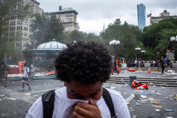 A person covers his face to protect from fireworks smoke at Union Square, New York, on Friday.