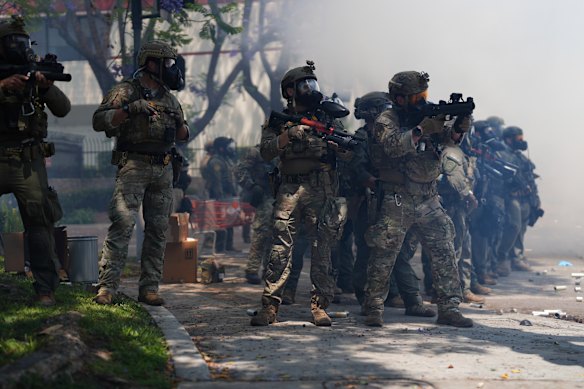 Law enforcement stand with weapons raised towards the protesters.