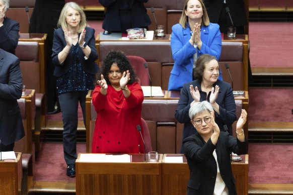 MPs including Assistant Minister for Indigenous Australians Malarndirri McCarthy (in red) and Penny Wong, Labor’s leader in the Senate, applaud after the Constitution Alteration Bill passed the Senate.