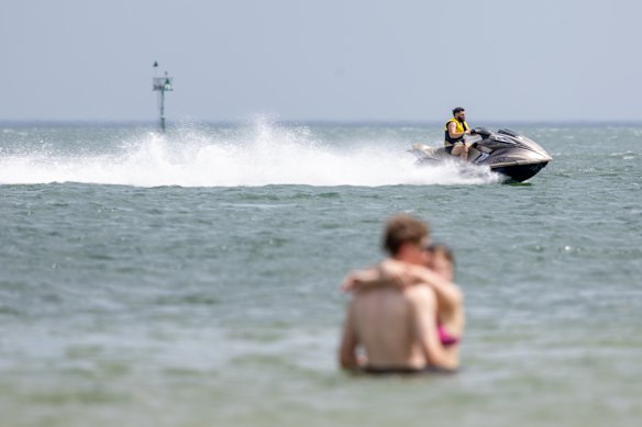 Swimmers share the water with a high-speed jet ski.