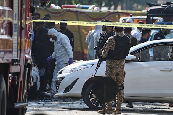 Pakistani investigators examine a damaged car at the site of a suicide bombing outside the gates of a district court, in Islamabad, Pakistan.