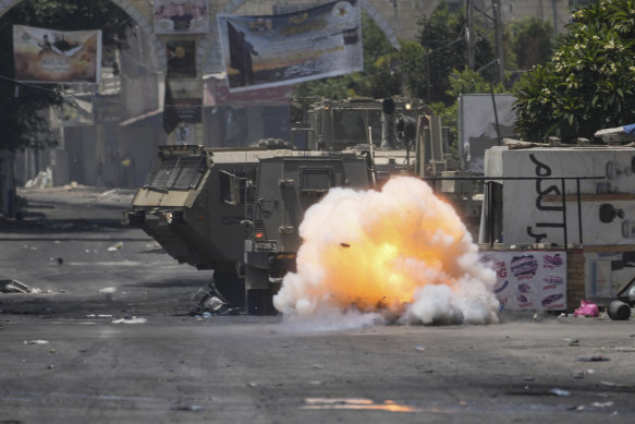 A bomb thrown by a Palestinian explodes next to an Israeli army vehicle during a military raid in the Jenin refugee camp.