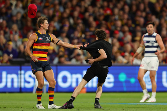 Adelaide’s Matt Crouch takes hold of a pitch invader in the third quarter of the round-two game against Geelong.