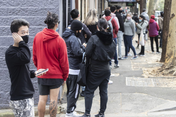 People outside a Sydney Centrelink office in July after lockdowns hit the city. UNSW research shows many will take a hit to their finances as assistance is cut by the federal government.