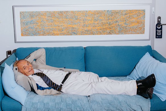Professor Alex McBratney in his office, on the coach he naps on,with one of his artworks above.