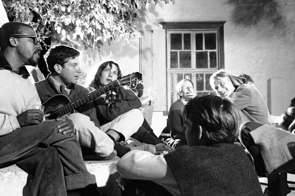 Leonard Cohen (segunda à esquerda) toca guitarra em Hydra com Charmian Clift (terceira à esquerda) e Marianne Jensen (também conhecida como Ihlen) em outubro de 1960. 