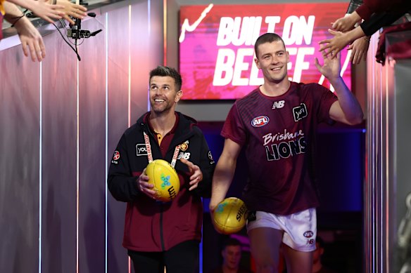 Josh Dunkley of the Lions runs out for the warm up. Lions leadership mentor Trent Cotchin (left) is alongside him.