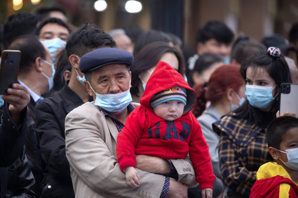 A man holds a child as they watch a dance performance at the International Grand Bazaar in Urumqi in Xinjiang. The region had the sharpest birthrate decline of any other in China between 2017 and 2019.