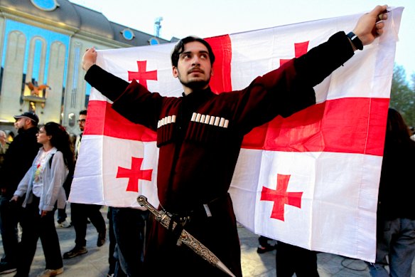 A demonstrator wearing a national costume holds a Georgian national flag attends a rally outside the parliament building in Tbilisi, Georgia, to protest against “the Russian law” similar to a law that Russia uses to stigmatise independent news media and organisations seen as being at odds with the Kremlin.