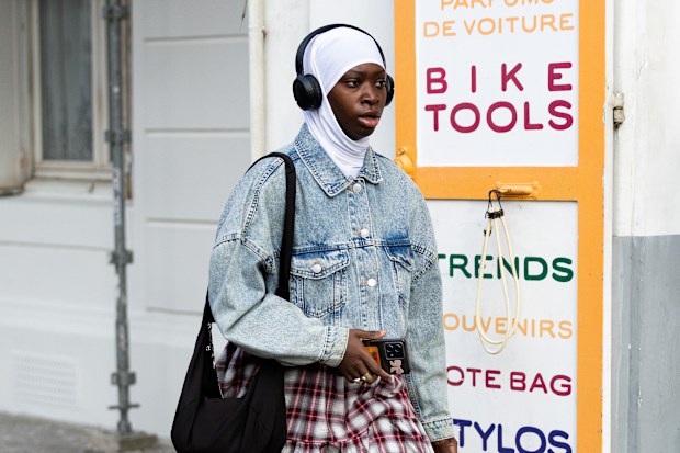 A guest wears a white headscarf, over-ear headphones, and no visible makeup details outside the Dior show during the Haute Couture Spring Summer 2026 as part of Paris Fashion Week on January 26, 2026 in Paris, France.