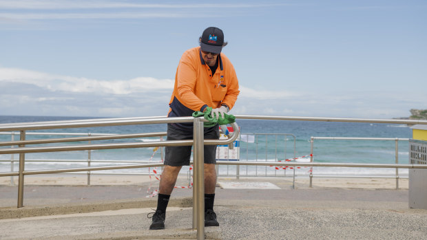 A Waverley Council worker cleans a railing at Bondi beach. While some council employees are busier than ever, others have been stood down because of coronavirus.