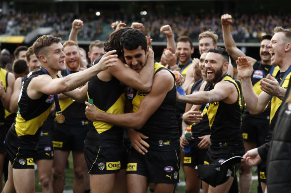 Marlion Pickett is embraced by Tiger teammates after their premiership victory.