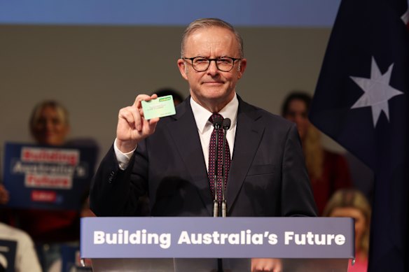 Prime Minister Anthony Albanese holds up his Medicare card at the rally.