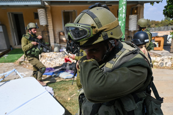 An IDF soldier covers his nose while walking past bodies after Hamas militants’ deadly attack on a kibbutz near the border with Gaza.