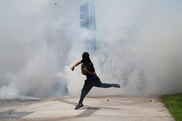 A protester throws a rock amid a cloud of tear gas released by law enforcement.