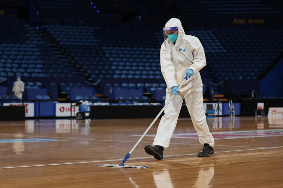 A staff member in PPE cleans the court following the round five Super Netball match between the Fever and the Giants.