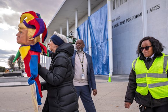 O pessoal de segurança fala com um manifestante enquanto trabalhadores acrescentam o nome do presidente Donald Trump ao Centro Memorial John F. Kennedy de Artes Cênicas, em Washington, na sexta-feira.