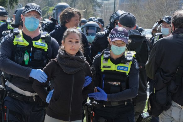 A woman is led from the protest by police.