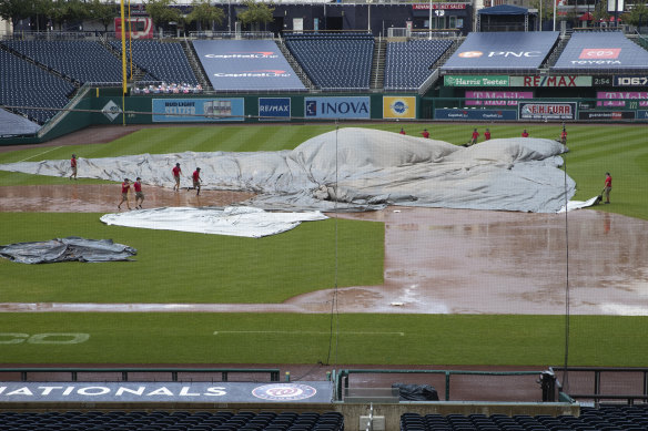 The Nationals Park grounds crew tries to untangle the tarp as rain buckets down in Washington.