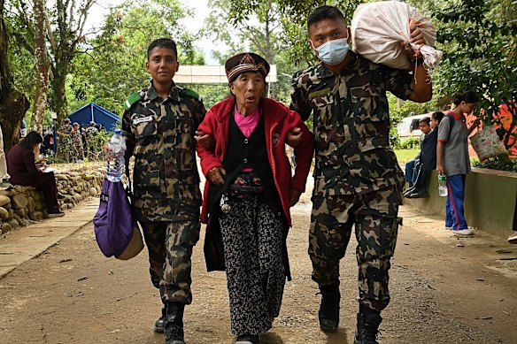 Nepalese soldiers assist an elderly woman.