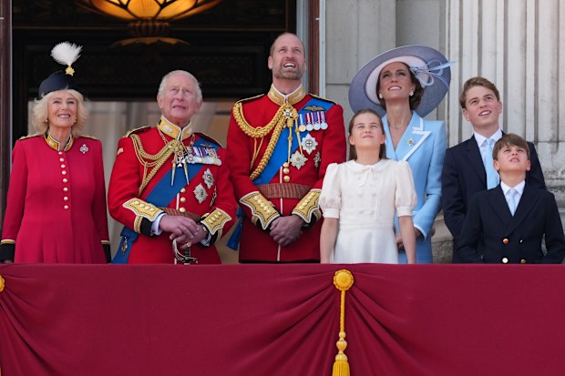 O rei Carlos III da Grã-Bretanha, segundo à esquerda, e a rainha Camilla, à esquerda, olham para cima enquanto observam a passagem de aviões militares da varanda do Palácio de Buckingham, com outros membros da família real, o príncipe William, a princesa Kate de Gales, a princesa Charlotte, o príncipe George e o príncipe Louis